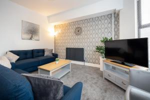 a living room with a blue couch and a flat screen tv at Spacious & Stylish 5 Bed with Free Street Parking in Morecambe