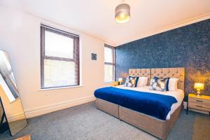a bedroom with a bed and a blue wall at Spacious & Stylish 5 Bed with Free Street Parking in Morecambe