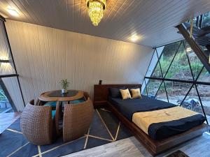 a bed and a table in a room with windows at Cabin Alpha in Bandarawela