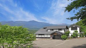 a building with a parking lot with mountains in the background at かっぱの宿旅館三治郎 in Zao