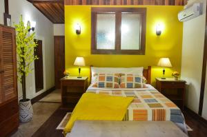 a yellow bedroom with a bed and two night stands at Pousada Dom Angelo in Paraty