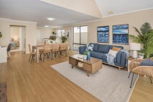ein Wohnzimmer mit einem blauen Sofa und einem Tisch in der Unterkunft Ocean Pearls in Busselton