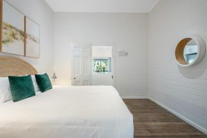 a white bedroom with a white bed and a mirror at Cove Quarters in Byron Bay +13 photos
