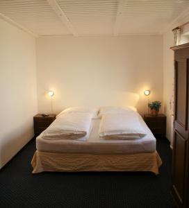 Frühstückpension Larson في باد هوفغاستين: غرفة نوم بسرير كبير مع مواقف ليلتين