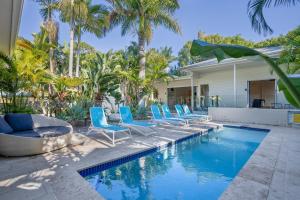 a pool with blue lounge chairs and palm trees at Cove Quarters in Byron Bay