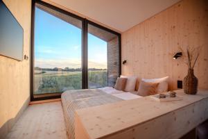 a bedroom with a bed with a large window at Ostsee Baumhaushotel - Auf Höhe der Baumkronen in Wangels