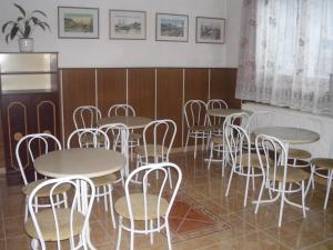 a dining room with tables and white chairs at Stop Panzio in Debrecen