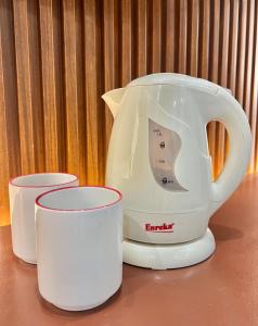 a white tea kettle and two cups on a table at Lipa City Transient Room in Inosloban +2 photos
