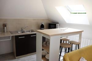 a kitchen with a sink and a counter with stools at Appartement 2 chambres in Charleville-Mézières
