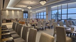 a dining room with tables and chairs and windows at SSK Urmee in Cox's Bazar