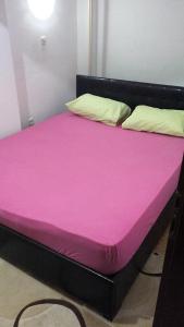a bed with pink sheets and pillows in a room at Hello Apartment in Skopje