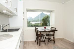 a kitchen with a table and chairs and a window at Frittliggende hjem med nydelig utsikt in Vestvågøya