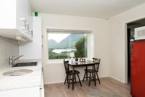 a kitchen with a table and chairs and a window at Frittliggende hjem med nydelig utsikt in Vestvågøya