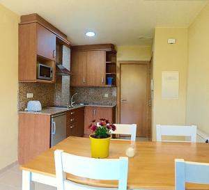 uma cozinha com uma mesa de madeira com um vaso de flores em Apartament Escaladei em Escaladei
