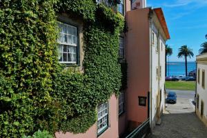 een gebouw bedekt met klimop naast de oceaan bij Casa da Belavista in Porto