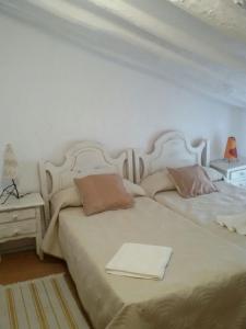 a bedroom with two beds and a table with a lamp at La Cueva Soleá in Algodonales