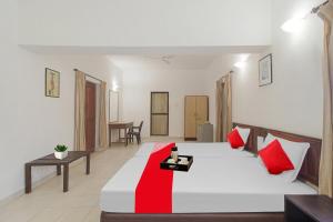 a bedroom with a large white bed with red pillows at Hotel O Halcyon Inn in Candolim