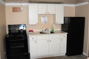 a kitchen with a black refrigerator and a sink at Bluebird Motel in Port Alberni