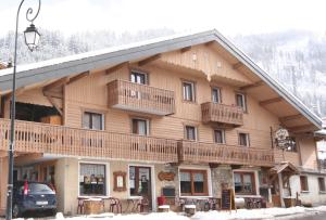 - un grand bâtiment en bois avec un balcon au-dessus dans l'établissement Hôtel l'Edelweiss, à Châtel