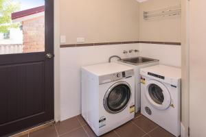 een wasruimte met een wasmachine en droger en een wastafel bij All Decked Out- WIFI, AC in bedrooms, Fireplace in Busselton