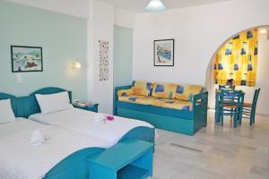 a bedroom with two beds and a couch and a table at Maroussa Studios in Agia Anna Naxos