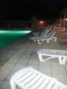 a row of white benches next to a swimming pool at night at Residence Le Fontane in Licciana Nardi