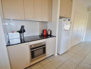 a kitchen with white cabinets and a white refrigerator at Sandpiper 8 - Close to Town and Beach in Inverloch
