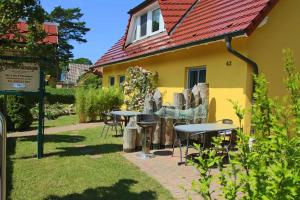 a yellow house with tables and chairs in the yard at Ferienwohnungen Fründt in Prerow