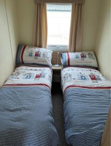 two beds in a small room with a window at M15 Meadow View Golden palm in Chapel Saint Leonards +4 photos
