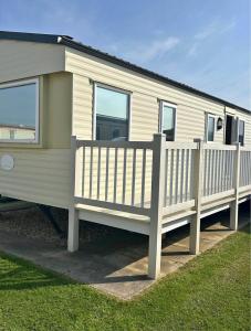 a white mobile home with a wooden fence at M15 Meadow View Golden palm in Chapel Saint Leonards