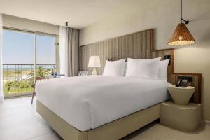 Un dormitorio con una gran cama blanca y una gran ventana. en Amarello Hotel Praia Santo André, Tapestry Collection by Hilton, en Santiago do Cacém