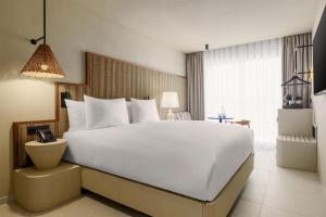 una cama blanca grande en una habitación de hotel en Amarello Hotel Praia Santo André, Tapestry Collection by Hilton, en Santiago do Cacém