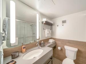 a bathroom with a sink and a toilet and a mirror at The Wildbirch Hotel - JdV by Hyatt in Anchorage