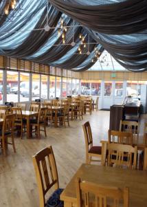 a restaurant with wooden tables and chairs and windows at Holiday home Golden Palm resort in Chapel Saint Leonards