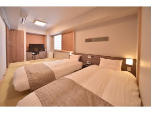 duas camas num quarto de hotel com televisão em Dormy Inn Abashiri em Abashiri