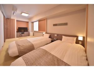 two beds in a hotel room with a television at Dormy Inn Abashiri in Abashiri