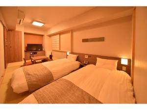 a hotel room with two beds and a television at Dormy Inn Abashiri in Abashiri