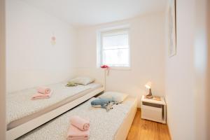 a white bedroom with two beds and a window at Apartment Alba with garden in Piran