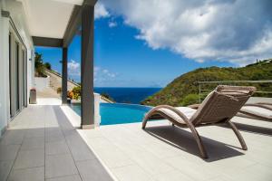 wiklinowy fotel siedzący na patio przy basenie w obiekcie Villa Angel Sunset w mieście Gustavia