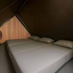 two white beds in a room with a wall at TK Coconut Camping in Tanjung Karang