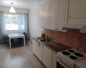 a kitchen with a stove and a sink and a table at LibO-apartment, Myllymäki 19 X in Lahti
