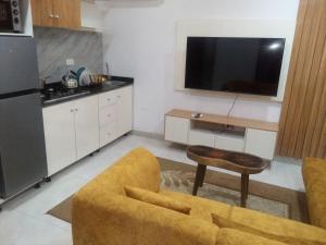 Una sala de estar con un sofá amarillo y una cocina. en Greens Apartment, en Lagos