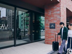 two people standing outside of a building with their luggage at FAV LUX Sapporo Susukino in Sapporo