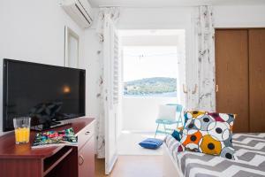a bedroom with a bed and a tv and a window at Hana Home - Apartments Tisno in Tisno