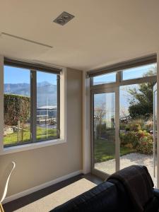 a living room with three windows and a couch at Queenstown Alpine Escape in Frankton