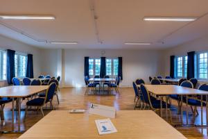 an empty room with tables and chairs and windows at Jegtvolden Fjordhotell in Straumen