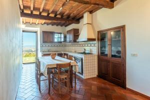 cocina con mesa, fogones y barra en Agriturismo La Rugiada, en Monteroni dʼArbia
