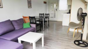 a living room with a purple couch and a table at Domki Bosman in Dziwnówek