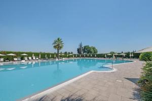 a large swimming pool with chairs and umbrellas at Ca' dei Vigneti in Colà di Lazise +34 photos