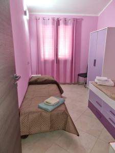 Dos camas en una habitación con paredes rosas. en Casa Alessia, en SantʼAnna Arresi